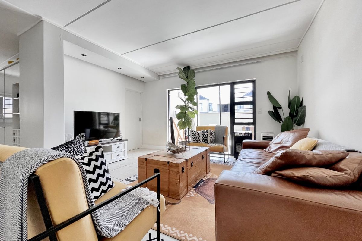 A bright and spacious living room featuring tiled flooring, recessed ceiling lighting, and a large sliding glass door providing access to the exterior.