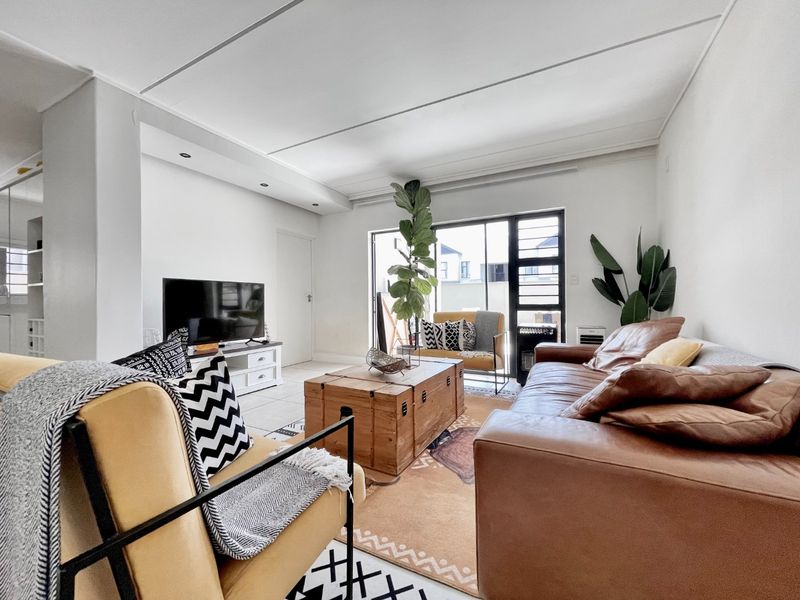 A bright and spacious living room featuring tiled flooring, recessed ceiling lighting, and a large sliding glass door providing access to the exterior.