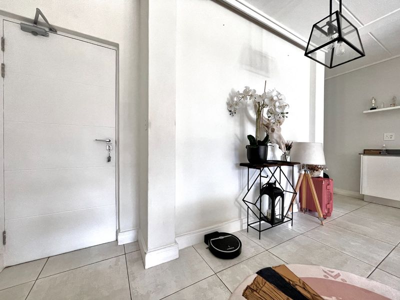A bright and clean entryway featuring neutral tiled flooring, a modern geometric pendant light, and a solid internal door.