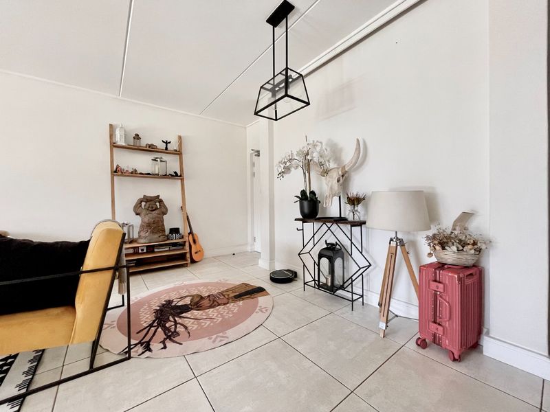 A bright living area featuring neutral tiled flooring and a modern geometric pendant light fixture.