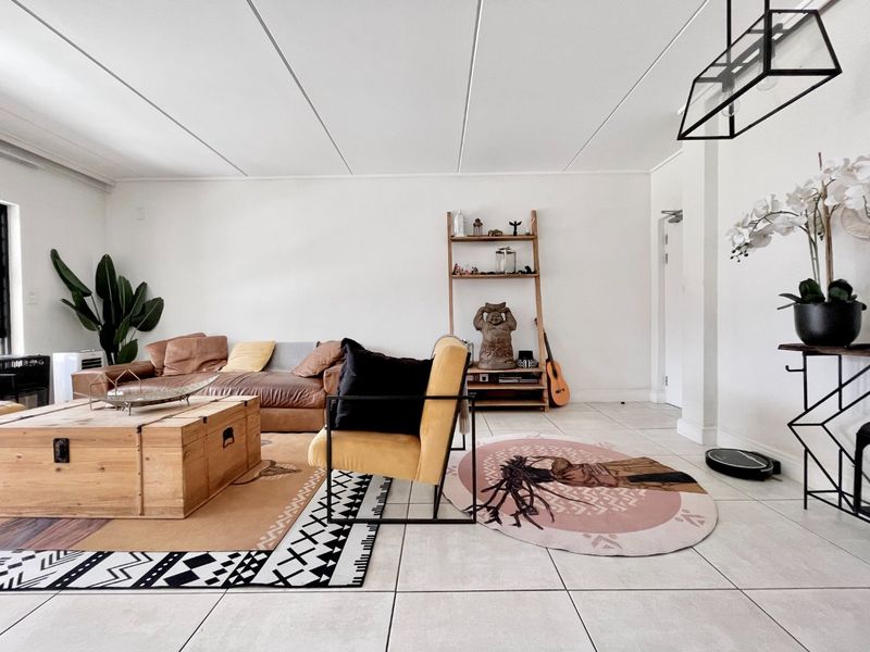 A bright and spacious living room featuring neutral tiled flooring and a modern suspended ceiling design, offering a clean and open living environment.