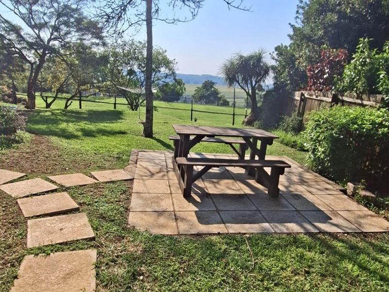 A well-maintained garden featuring a paved patio area, stone stepping path, and scenic views of the surrounding landscape.