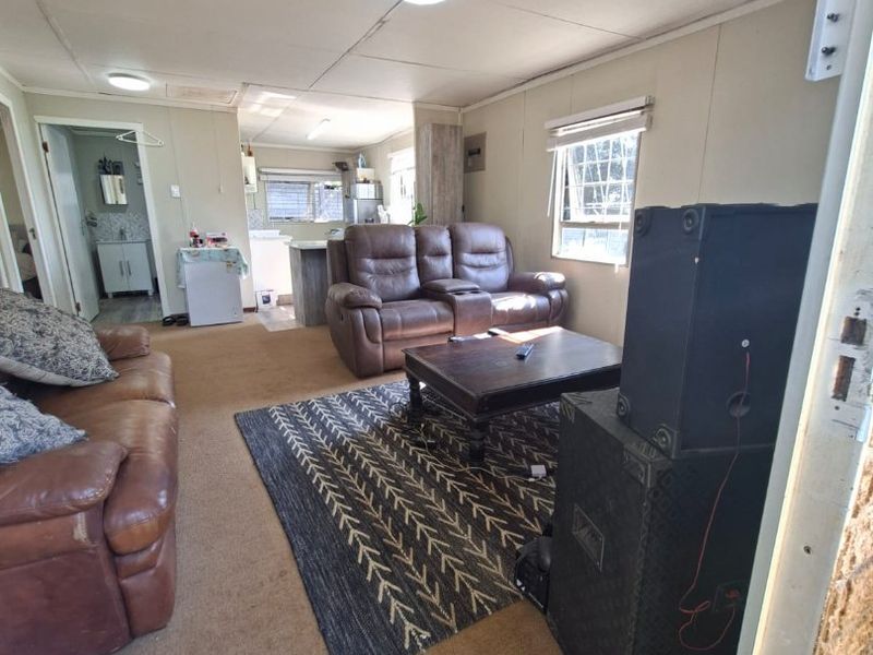 Open plan living area featuring carpeted flooring and connected kitchen and bathroom access, showing dated finishes and potential for modernization.