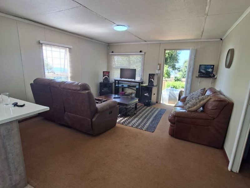 A living room area featuring carpet flooring, ceiling tiles, and direct access to an outdoor space through a glass door.