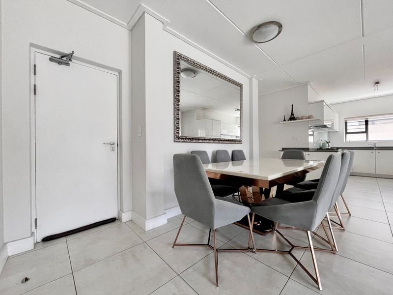 An open-plan dining and kitchen area featuring neutral tiled flooring, modern cabinetry, and a clean, bright aesthetic suitable for contemporary living.