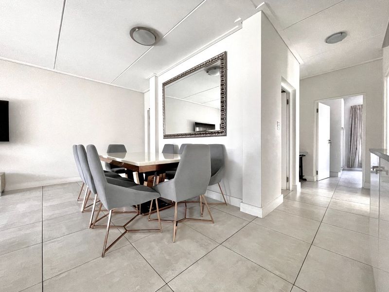 A bright and spacious dining area featuring neutral tiled flooring and clean, modern finishes, providing a versatile space for family meals and entertaining.