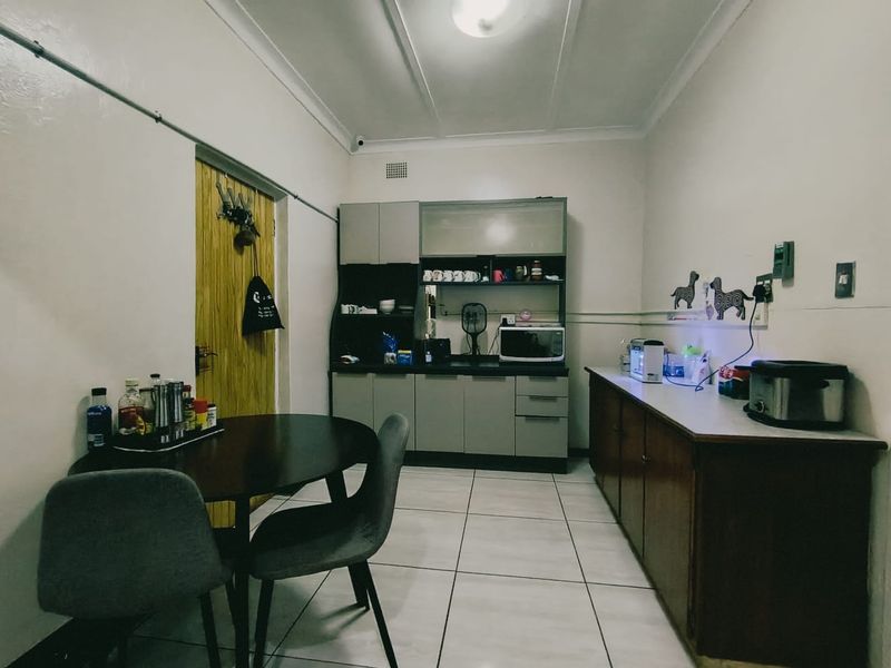 A functional kitchen area featuring built-in cabinetry, laminate countertops, and tiled flooring, providing a practical space for meal preparation and dining.