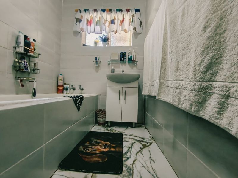 A functional bathroom featuring a bathtub, vanity cabinet with basin, and tiled finishes throughout.