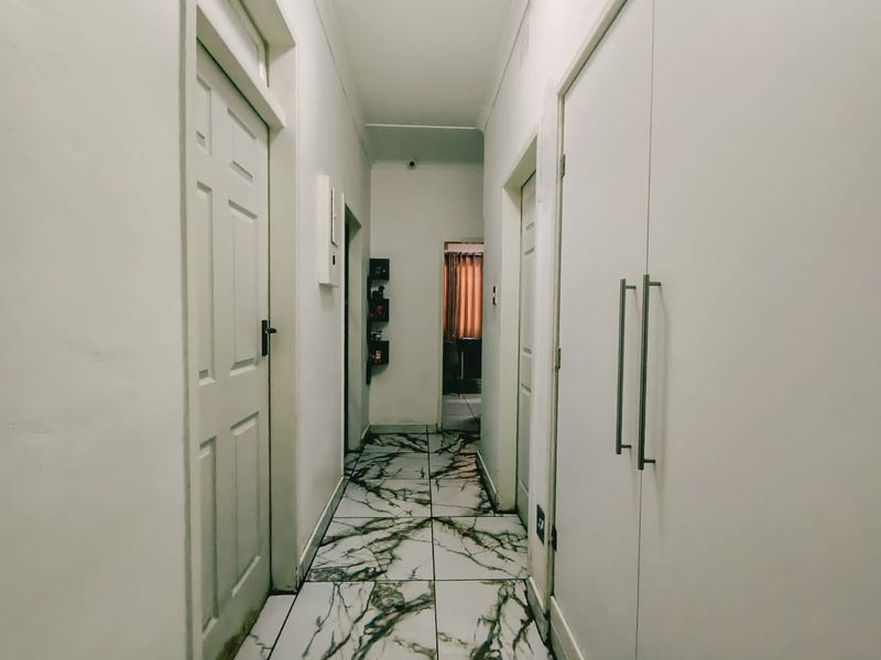A clean, functional hallway featuring modern marble-look floor tiles and built-in storage cupboards, providing efficient access to adjacent rooms.