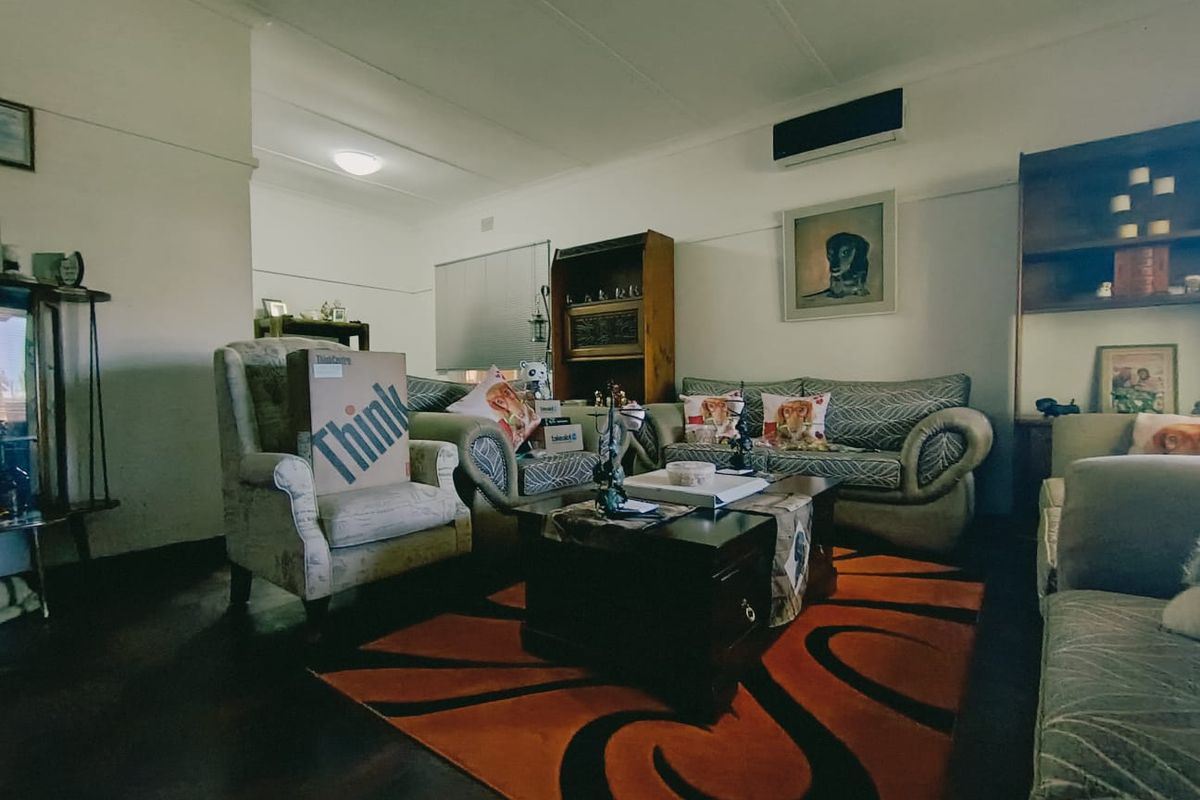 A living room featuring timber flooring, a coved ceiling, and a wall-mounted split-system air conditioner.