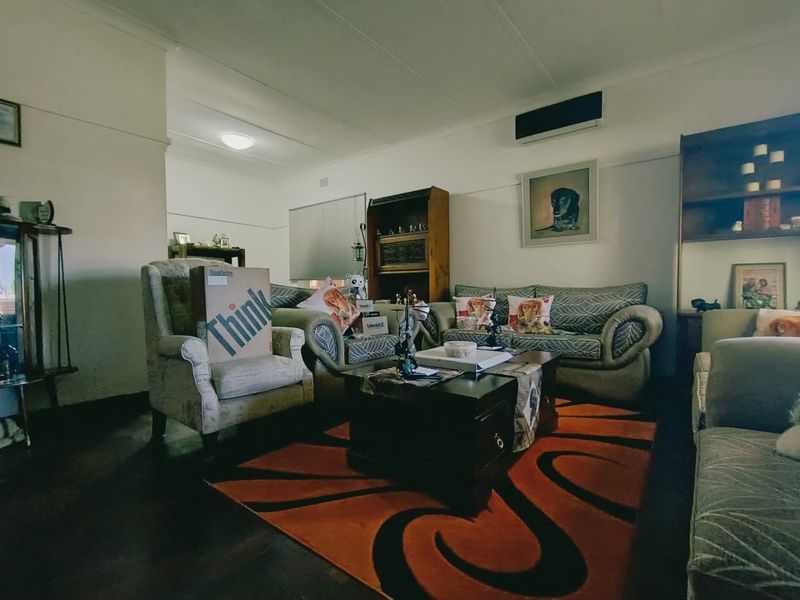 A living room featuring timber flooring, a coved ceiling, and a wall-mounted split-system air conditioner.