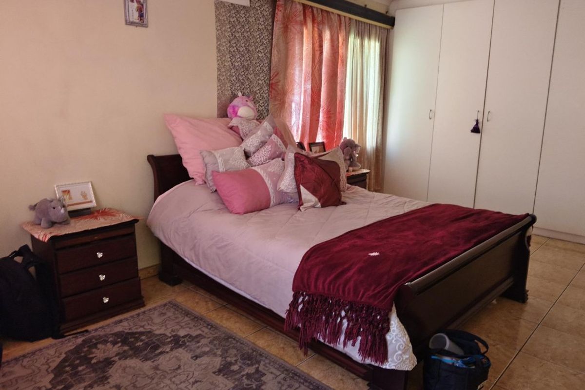 A bedroom featuring built-in cupboards and tiled flooring, offering a functional space with neutral wall finishes.