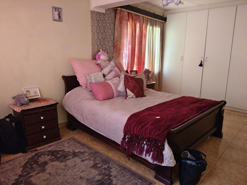 A bedroom featuring built-in cupboards and tiled flooring, offering a functional space with neutral wall finishes.