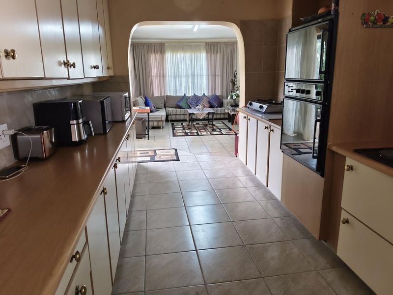 Open plan kitchen and living area featuring tiled flooring, built-in cabinetry, and a double oven, connected by a classic arched doorway.
