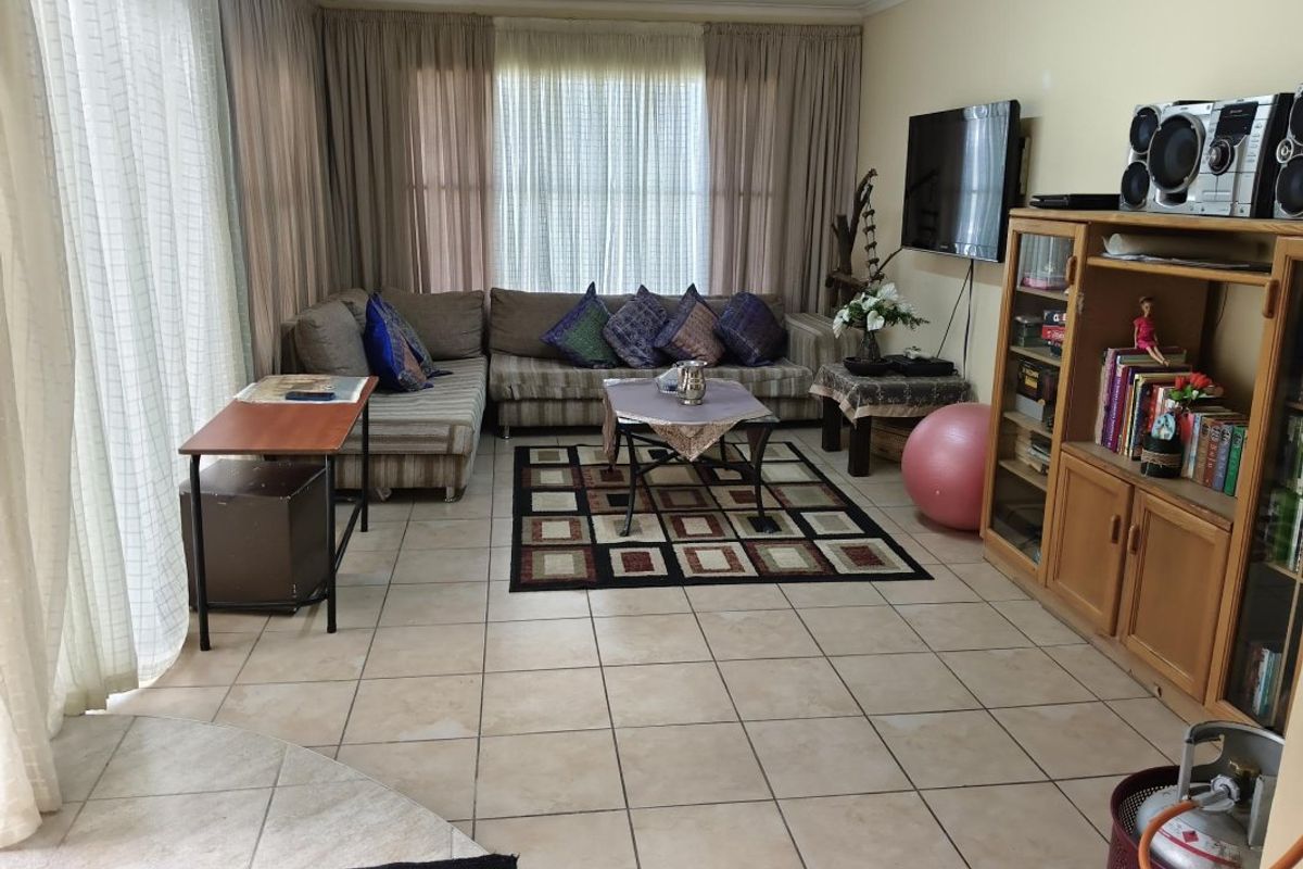 A living room featuring tiled flooring and large sliding glass doors that provide natural light, offering a functional space for relaxation.