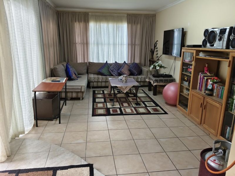 A living room featuring tiled flooring and large sliding glass doors that provide natural light, offering a functional space for relaxation.