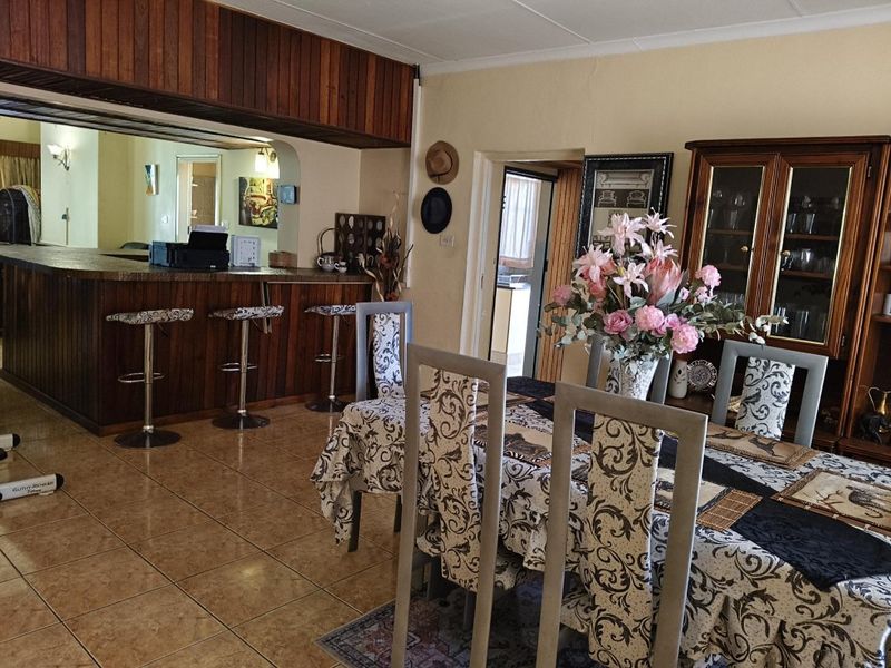 Open plan dining area featuring tiled flooring and a built-in wooden breakfast bar, creating a functional space for meals and casual entertaining.