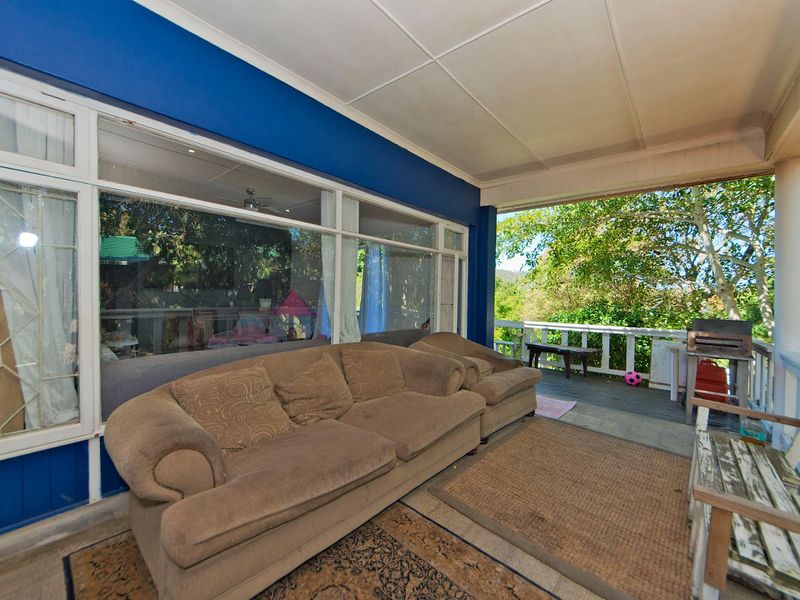 A covered outdoor patio area featuring timber decking, large glass sliding doors, and a railing overlooking the garden.