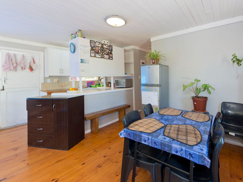 Open plan kitchen and dining area featuring timber flooring, tongue and groove ceiling, and a functional kitchen layout with a breakfast bar.
