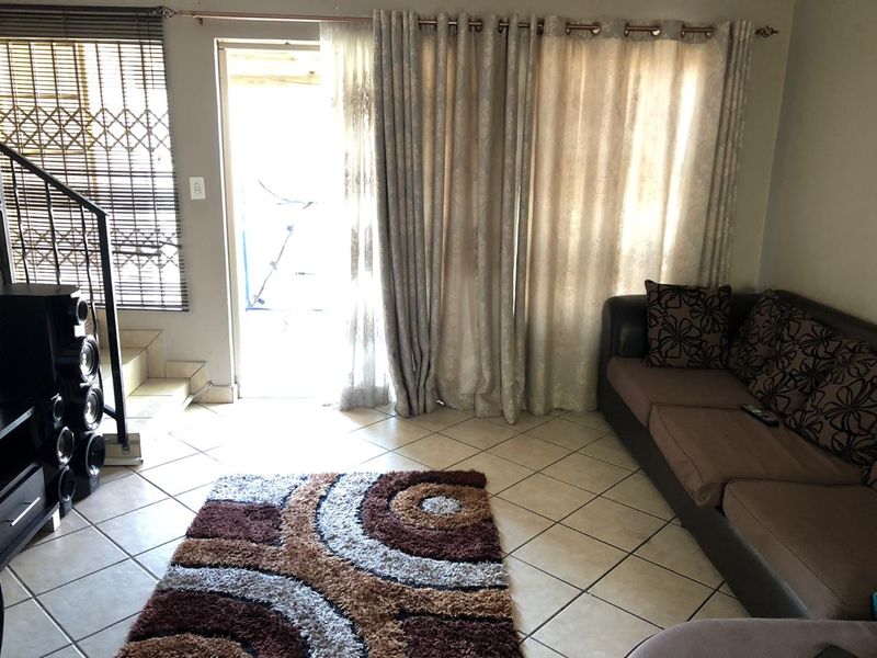 A living room featuring tiled flooring, a staircase with a security gate, and a sliding door leading to an outdoor area.