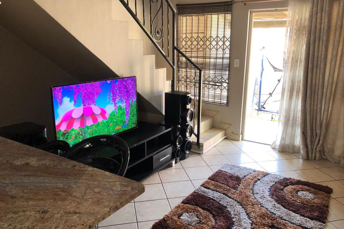 Living area featuring tiled flooring, a wrought iron staircase railing, and direct access to an outdoor patio through a sliding glass door.