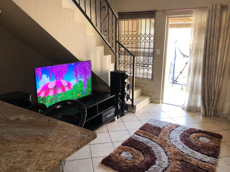 Living area featuring tiled flooring, a wrought iron staircase railing, and direct access to an outdoor patio through a sliding glass door.