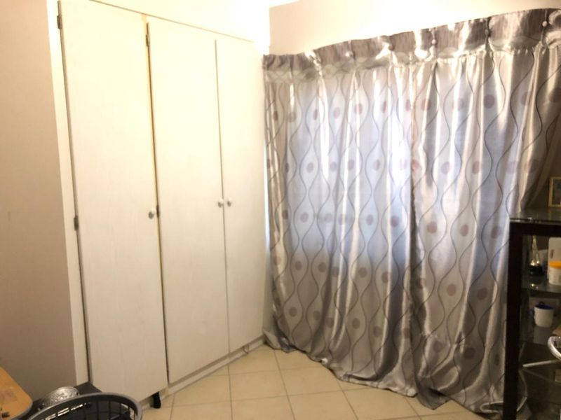 A bedroom featuring built-in cupboards and tiled flooring, offering a functional space with potential for modern updates.