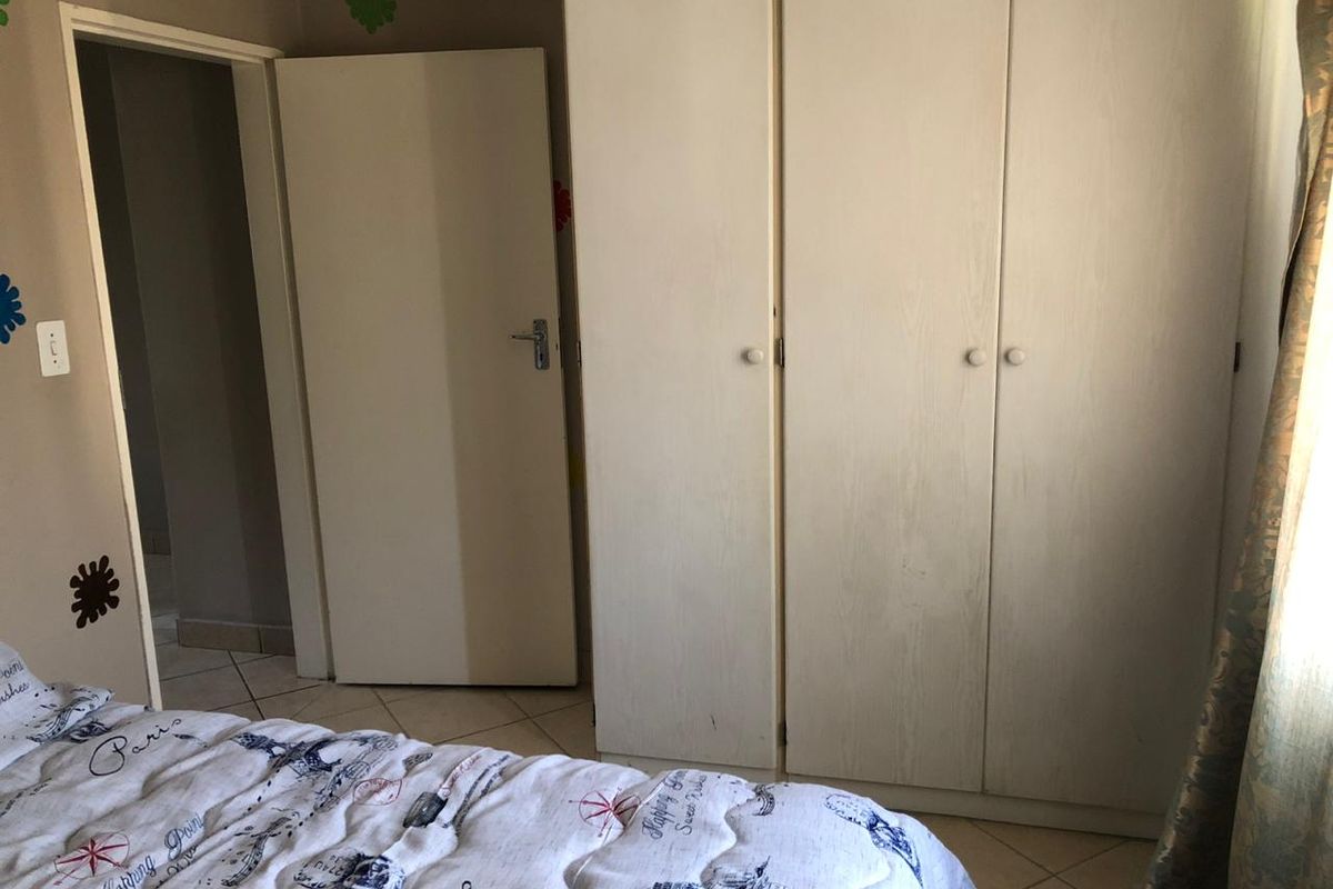 A bedroom featuring built-in cupboards and tiled flooring, providing functional storage space within the townhouse.