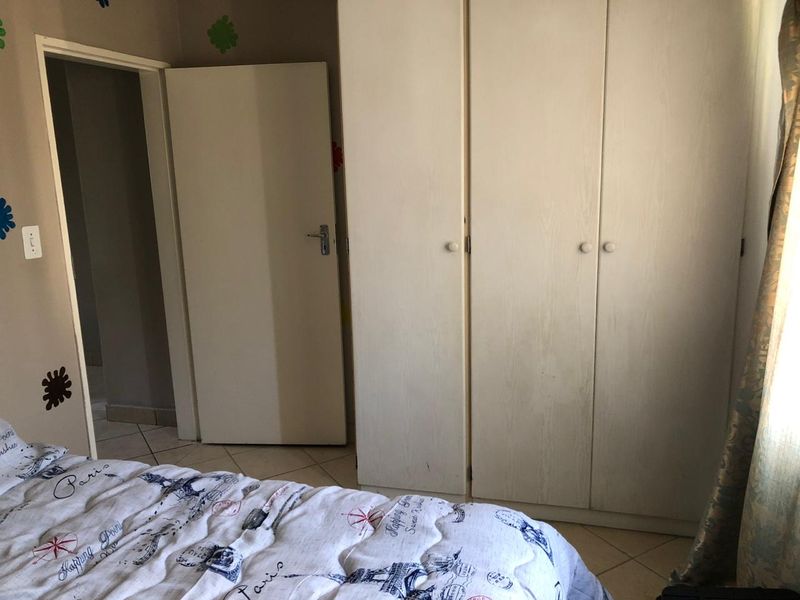 A bedroom featuring built-in cupboards and tiled flooring, providing functional storage space within the townhouse.