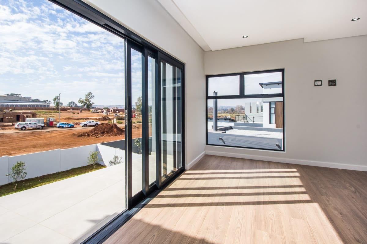 Bright and modern living area featuring high-quality laminate flooring, large sliding glass doors, and expansive windows offering natural light and views.