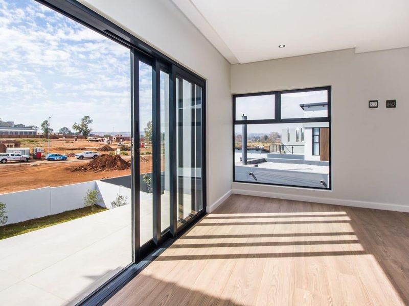 Bright and modern living area featuring high-quality laminate flooring, large sliding glass doors, and expansive windows offering natural light and views.