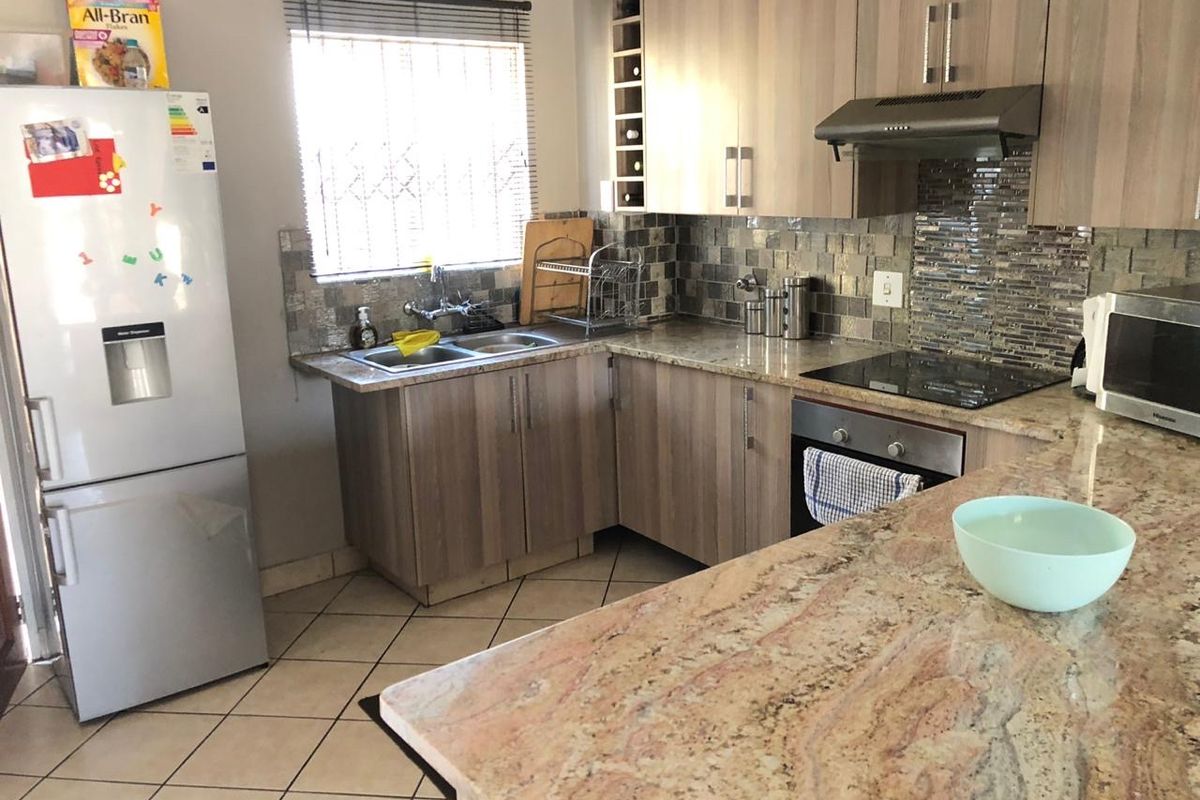 Functional kitchen featuring granite countertops, mosaic tile backsplash, built-in oven, electric hob, and ample laminate cabinetry with integrated wine storage.