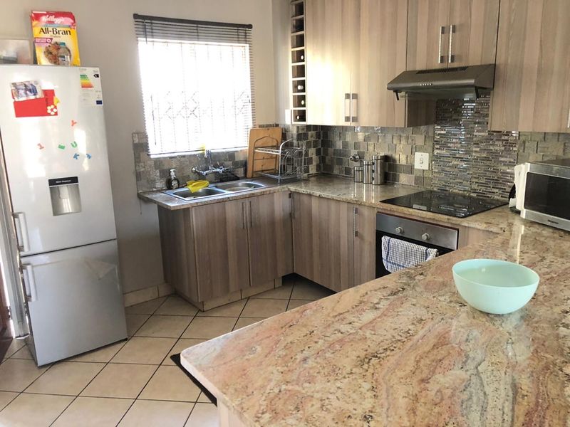 Functional kitchen featuring granite countertops, mosaic tile backsplash, built-in oven, electric hob, and ample laminate cabinetry with integrated wine storage.