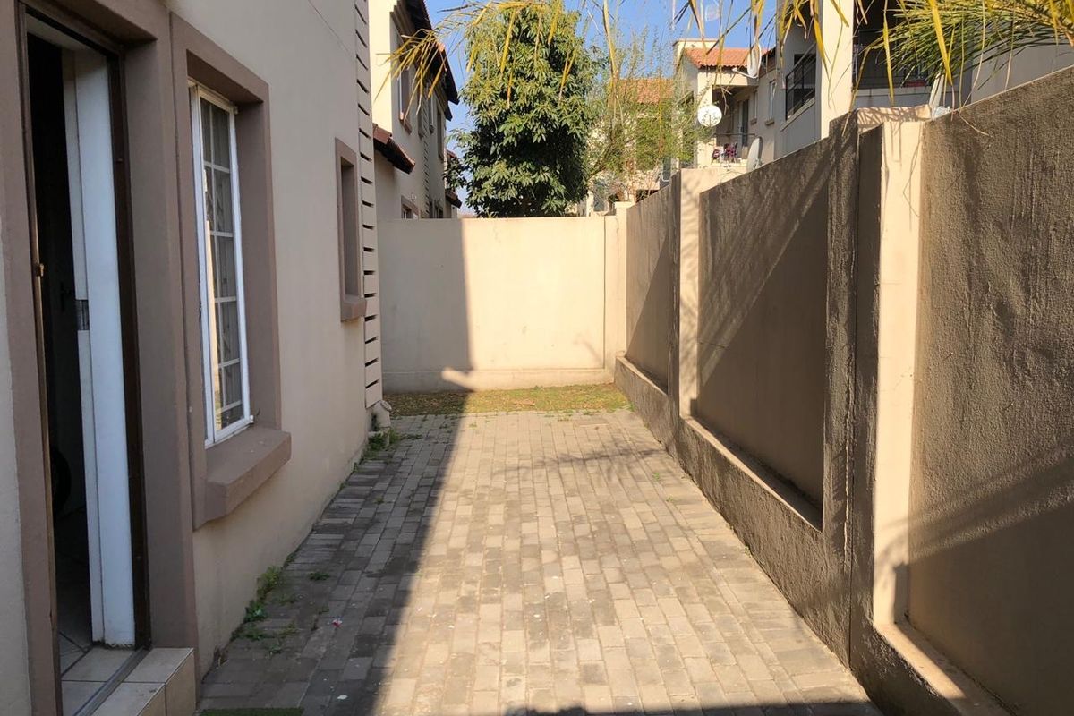 A paved rear courtyard area enclosed by high boundary walls, providing a private outdoor space accessible from the main dwelling.