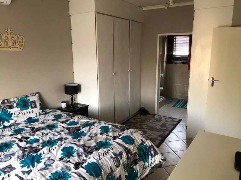 Bedroom featuring built-in cupboards and tiled flooring, with direct access to an en-suite bathroom.