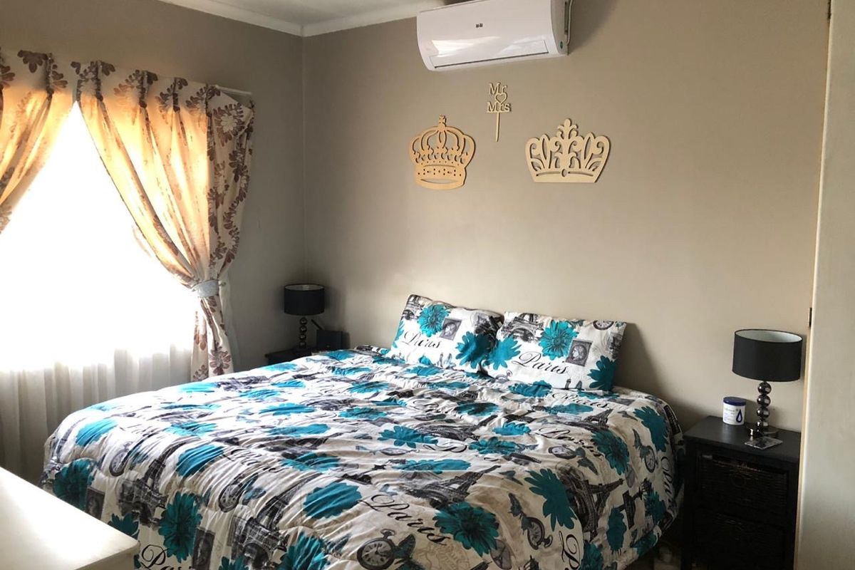 A comfortable bedroom featuring a wall-mounted split-system air conditioner and neutral wall tones, providing a functional space for rest.