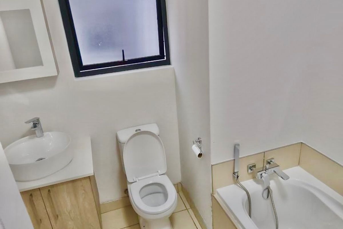 A functional bathroom featuring a vessel sink with vanity, a standard toilet, and a bathtub with a handheld shower mixer.