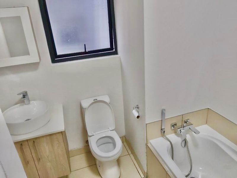 A functional bathroom featuring a vessel sink with vanity, a standard toilet, and a bathtub with a handheld shower mixer.