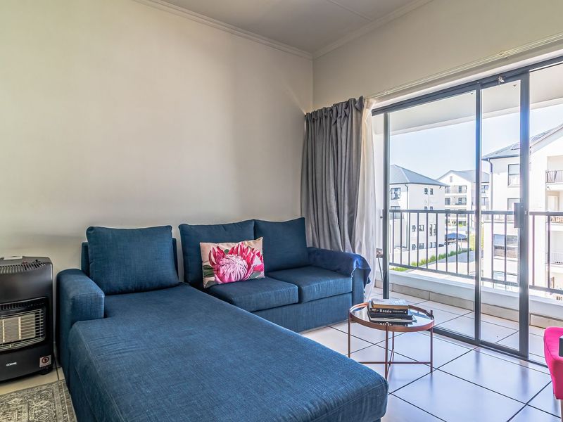 A bright living room featuring tiled flooring and large sliding glass doors that open onto a private balcony.