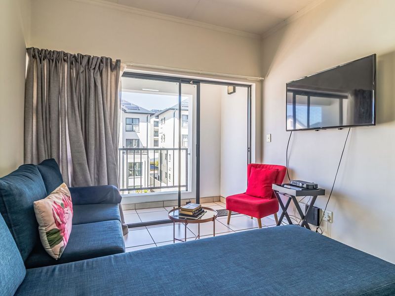 A living room featuring tiled flooring and a sliding glass door providing direct access to a private balcony.