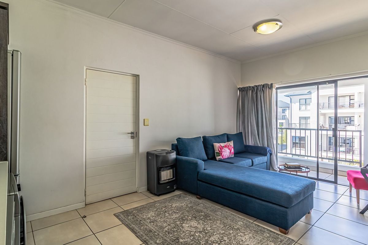 A bright living room featuring tiled flooring and a sliding glass door providing access to a private balcony.