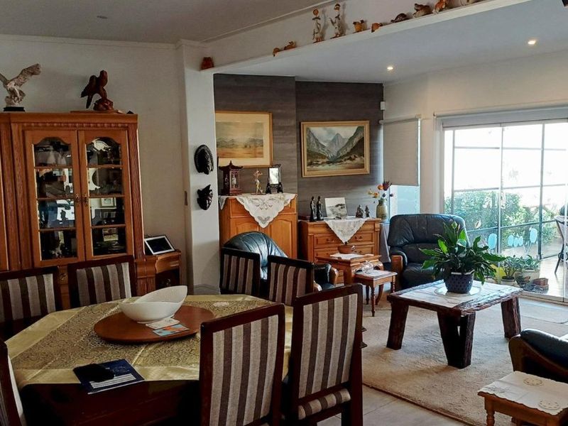 Spacious open-plan living and dining area featuring tiled flooring, recessed lighting, and large sliding glass doors providing access to the outdoor patio.