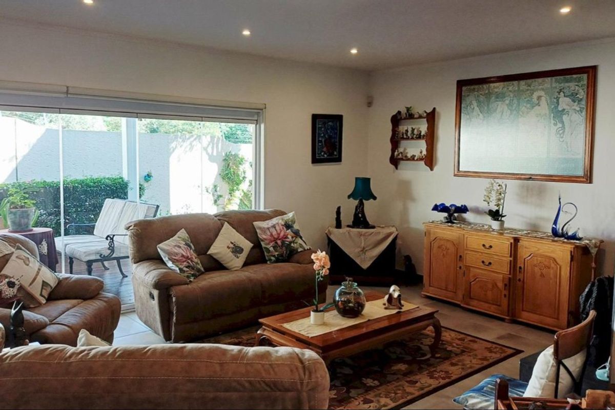A comfortable living room featuring recessed downlights, tiled flooring, and large sliding glass doors that provide direct access to the outdoor patio area.