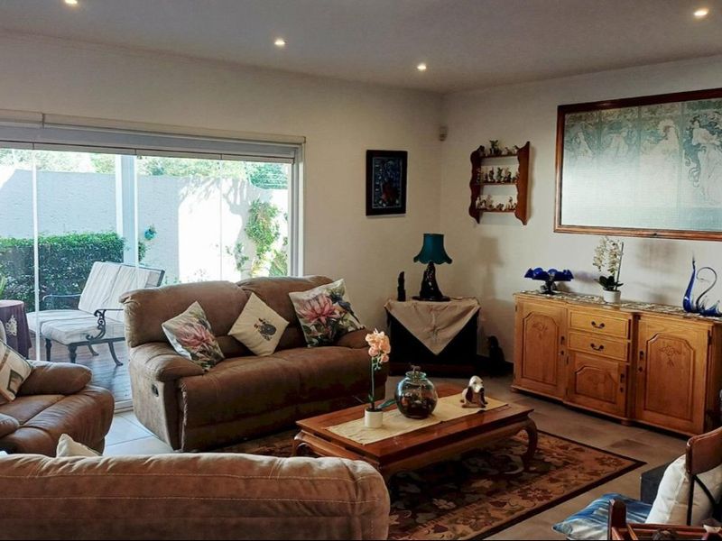 A comfortable living room featuring recessed downlights, tiled flooring, and large sliding glass doors that provide direct access to the outdoor patio area.