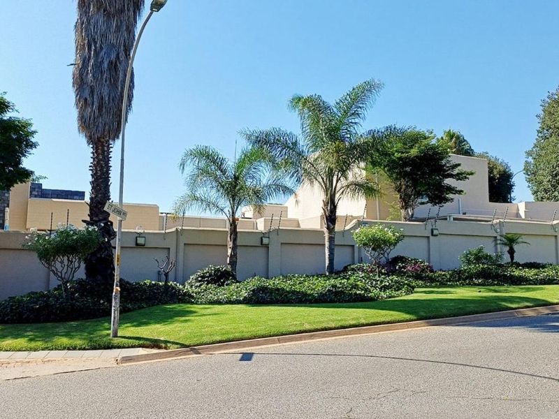 Street view of the property featuring a well-maintained perimeter wall with integrated electric fencing and landscaped garden verge.