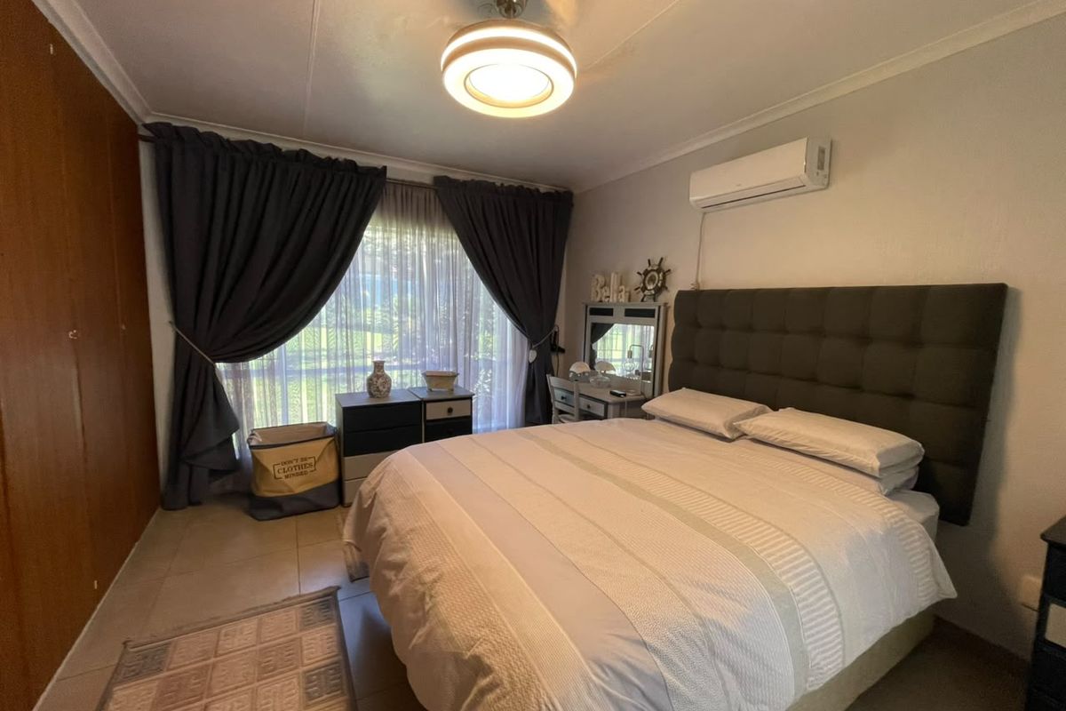 A well-maintained bedroom featuring tiled flooring, built-in cupboards, and a wall-mounted air conditioning unit.
