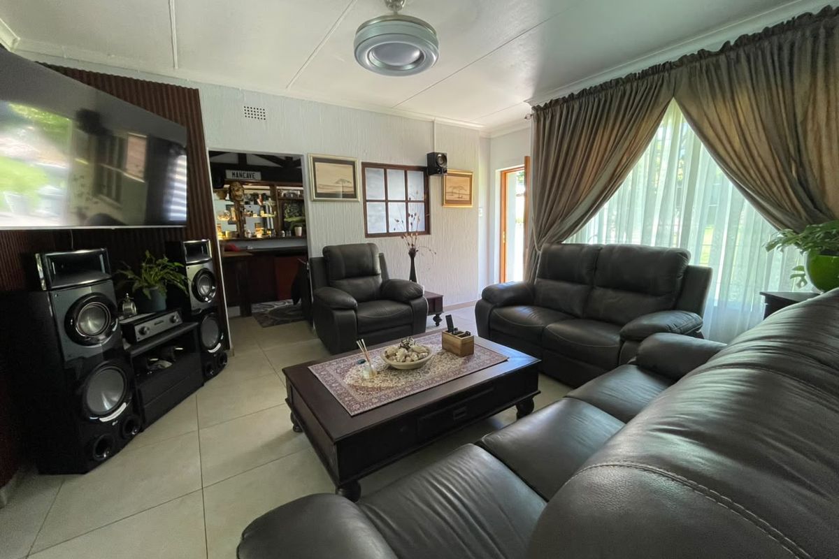 A comfortable living room featuring tiled flooring, a ceiling fan, and an internal window looking through to an adjacent space.