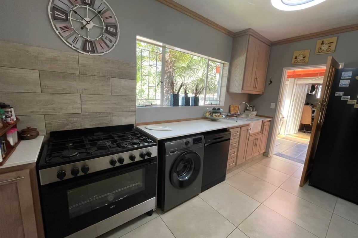 A functional kitchen featuring light wood cabinetry, a gas stove with oven, tiled backsplash, and a farmhouse-style apron sink with ample counter space.