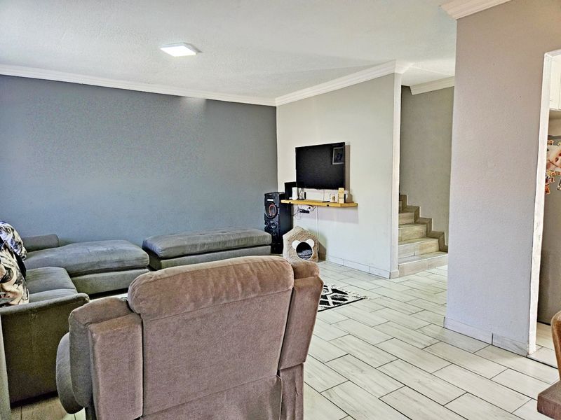 A spacious living room featuring tiled flooring, a staircase leading to the upper level, and neutral wall finishes.