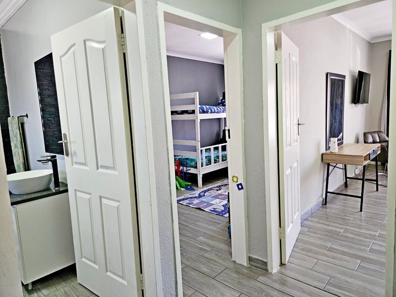 A hallway view showing access to a bathroom and bedroom, featuring tiled flooring and neutral wall finishes.